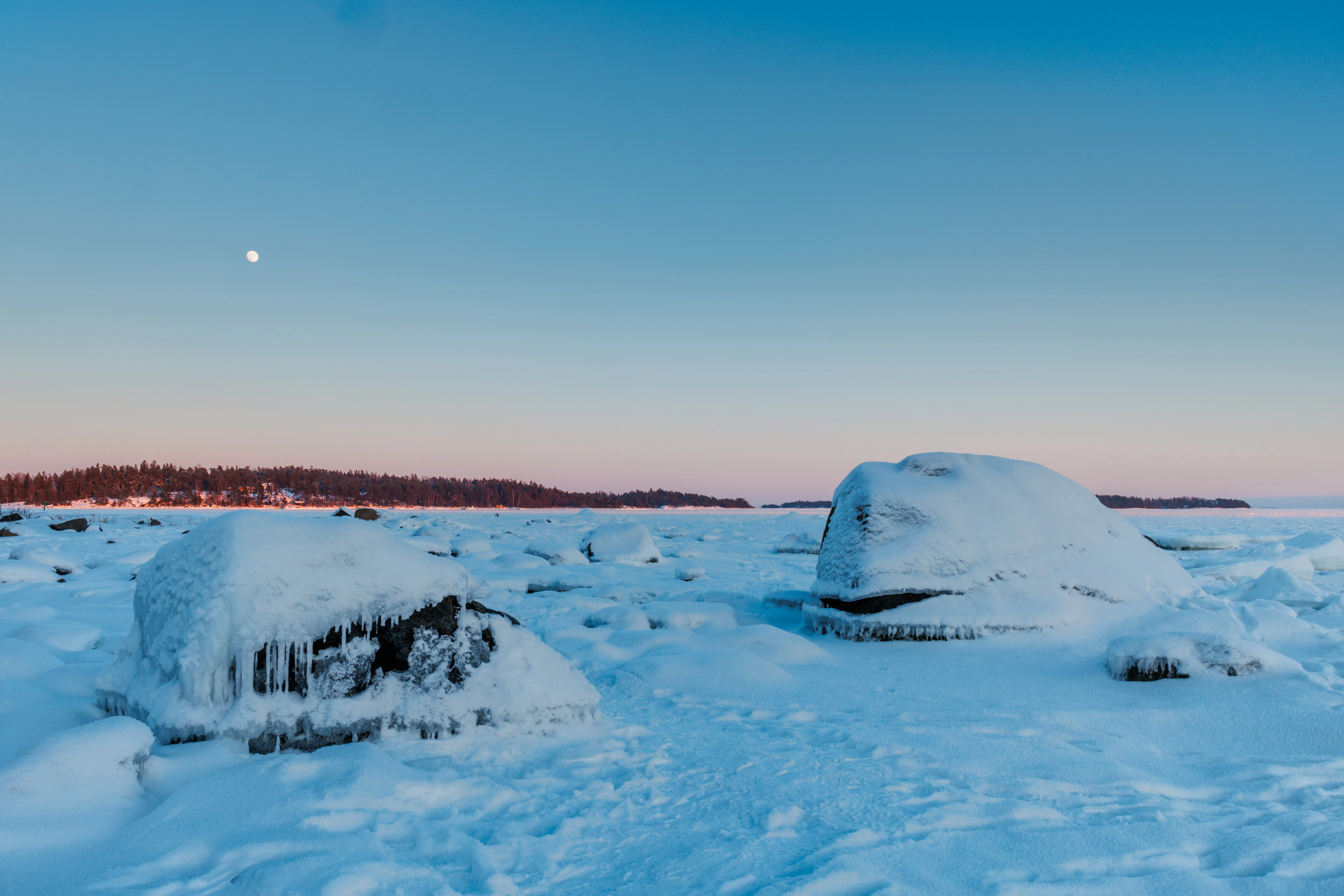 Moon over an icy winter landscape during blue hour