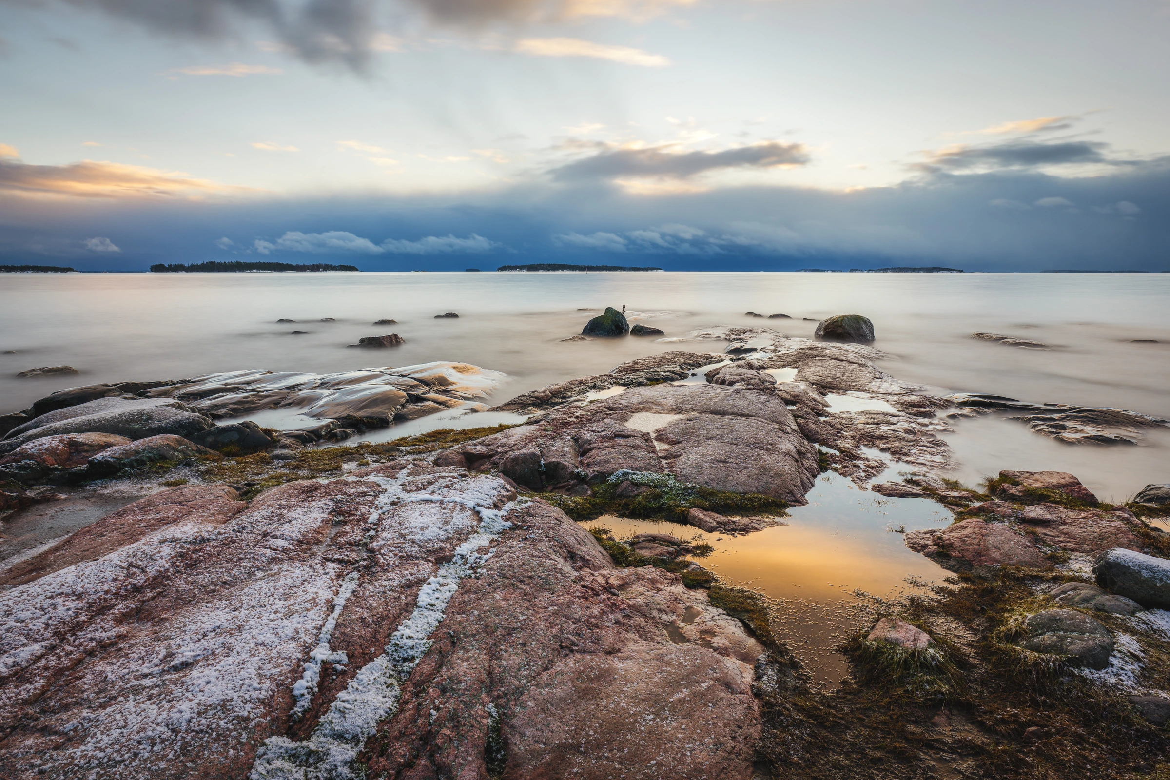 Sunset light over a rocky shoreline and distant islands